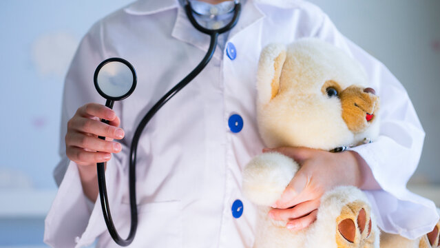 Child playing doctor with teddy bear. Image with selective focus