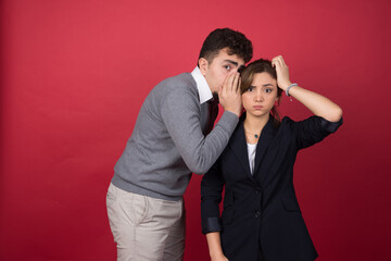 Young man tells some news to his girlfriend on red background