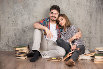 Obraz premium Photo of young couple sitting on the floor with books