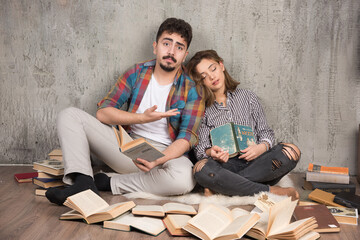 Image of pretty couple sitting on the floor with a lot of books