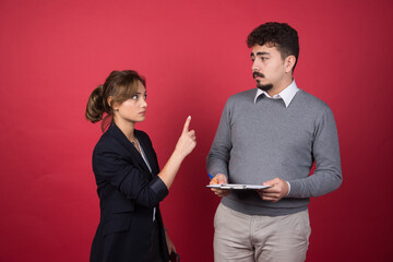 Serious woman looking at man with a clipboard angrily