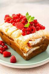 Rich sweet pie with fresh fruits, decorated with red currants and raspberries, in a plate on a pink background