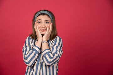 Cute girl with headband holding her face with happy expression