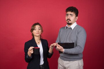 Young woman holding a cup of drink near young man with a clipboard