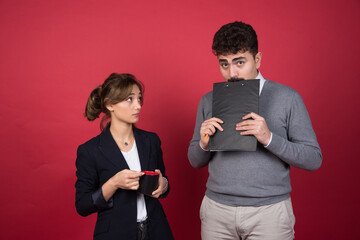 Young woman with cup of drink looking at young man with a clipboard