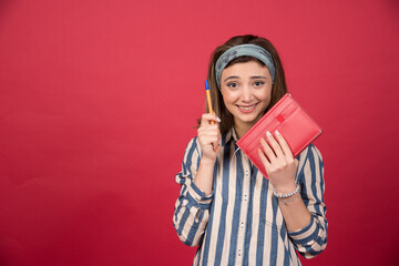 Young female student showing book and pen