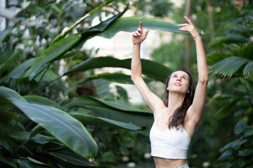 Female meditating and practicing yoga in tropical rainforest. Beautiful young woman practicing yoga outdoor with tropical forest in background.