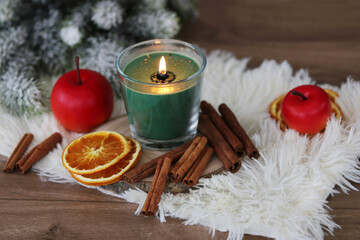 Aromatherapie und Entspannung. Duftkerzenglas mit Zimtstangen, Orangenscheiben und Tannenzweigen.