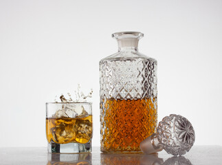 a carafe of whiskey next to a glass of whiskey with scattered splashes