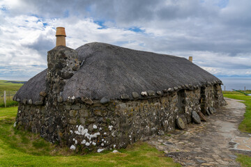 close-up view of a typical crofter cottage with thick stone walls and a thatched reed roof - obrazy, fototapety, plakaty