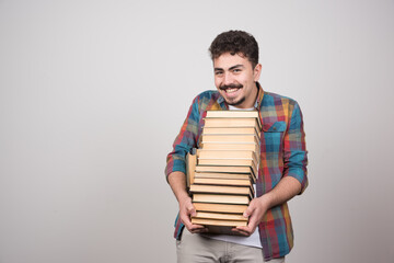 Young male student with pile of books posing to camera