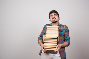 Young male student with pile of books feeling tired