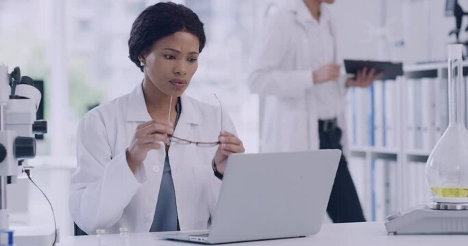 Stressed scientist working on a laptop in a lab. Worried and unhappy woman struggling with burnout, tension and a frustrating headache. Feeling anxious about difficult research while making mistakes