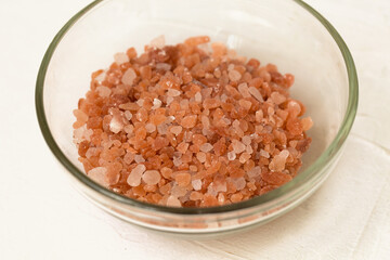 Pink crystal Himalayan salt in a glass bowl close up.