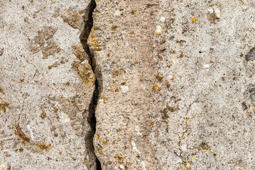 Large crack running vertical through a cement wall.Cracked stone wall background.black,gray cracked floor texture.Closeup.