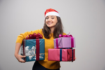 Young woman in Santa hat carrying Christmas presents