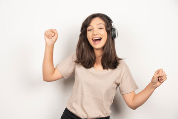 Young woman listening to music in headphones on white background
