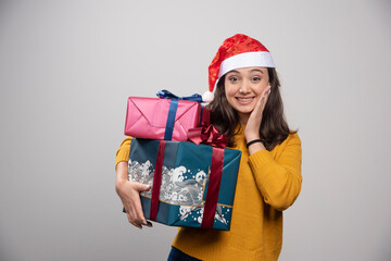 Smiling woman in Santa Claus red hat with Christmas presents