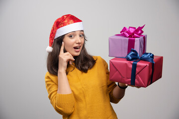Young woman in Santa hat carrying Christmas presents