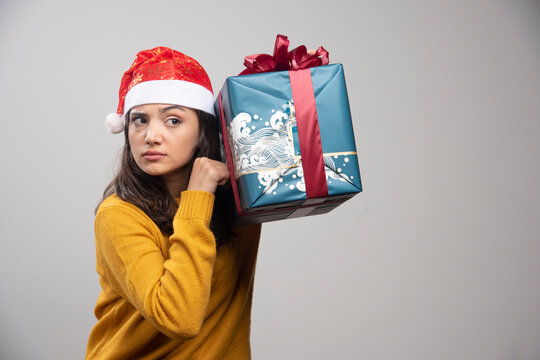 Young woman in Santa hat holding gift box