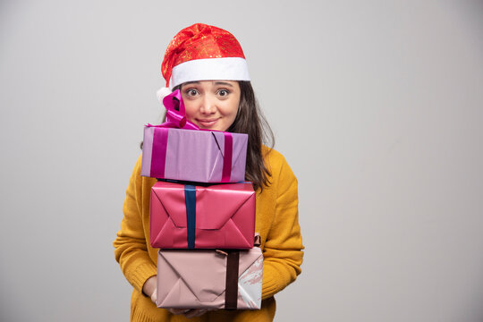 Smiling woman in Santa hat holding gift boxes