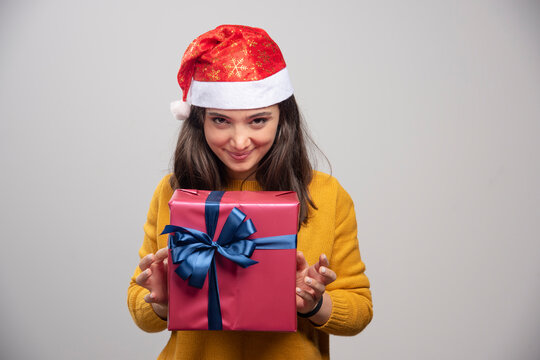 Happy woman in Santa hat holding gift box