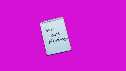 We are hiring Hand writing note on a notebook. lifestyle, advice, support motivational positive words are written on a solid background. Business, signs, symbols, concepts. Copy space.