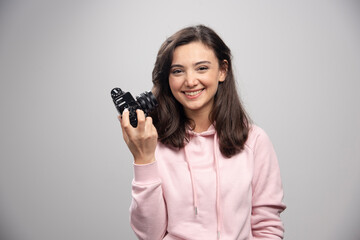 Female photographer smiling with camera on gray background