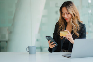 young woman holding credit card and using a laptop computer online shopping, eCommerce, internet banking, spend money, office work ideas