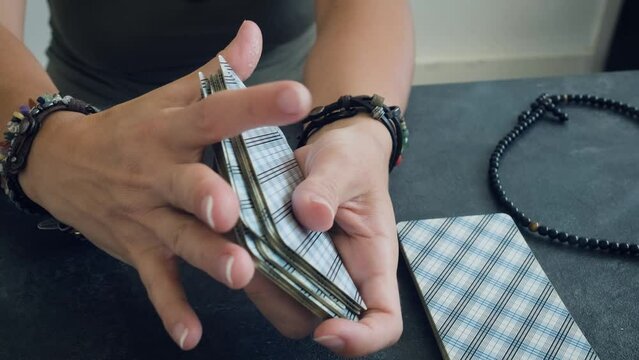 women's hands shuffle a deck of tarot cards
