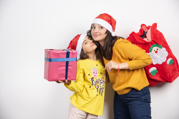 Young girl with present hugging woman with bag of presents