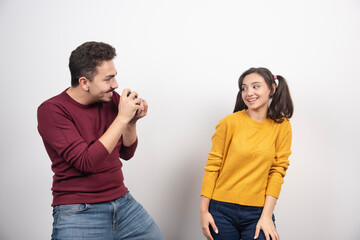 Man taking a picture of young woman on a white wall