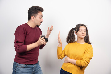 Cute couple with camera posing over a white wall