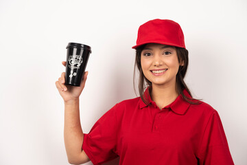 Woman in red uniform showing a cup of coffee on white background