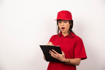 Young worker with red uniform and clipboard on white background