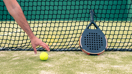 One caucasian man catch a yellow ball near the padel racket on green court grass