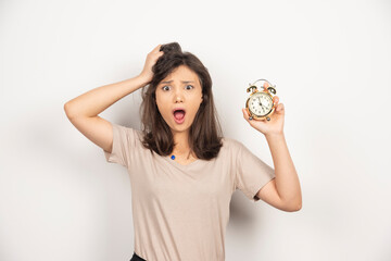 Young woman holding alarm clock on white background