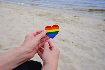 Rainbow heart from paper in woman hands. LGBT flag. LGBTQIA Pride Month in June. Lesbian Gay Bisexual Transgender. Gender equality. Human rights and tolerance. Rainbow flag 