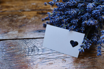 Mockup of a greeting card or card for wishes and a bouquet of lavender on a wooden background....
