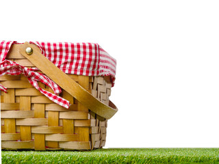 Straw picnic basket on a green lawn on a white background. The concept is rest, picnic, relaxation....