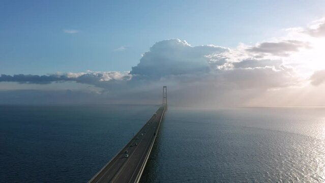 Car traffic at the Great Belt suspension bridge (&Oslash;stbroen) highway at sunset, Denmark, aerial footage