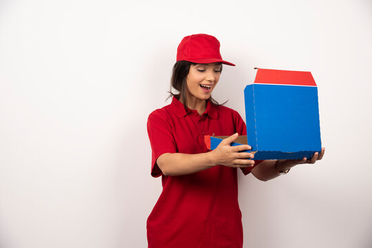 Female pizzaman courier opening a box of pizza on white background