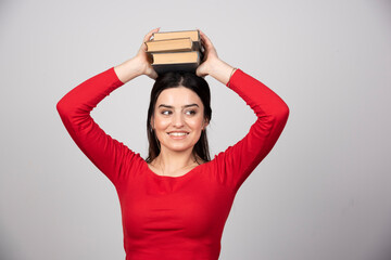 Photo of a funny woman holding books overhead