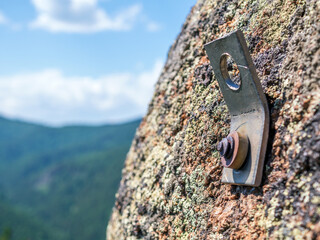 Rock climbing piton (also called a pin or peg) on the stone rock. Close-up, selective focus - obrazy, fototapety, plakaty