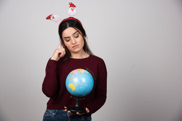 Young woman in Christmas headband looking at an Earth globe