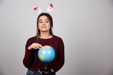 Young woman in Christmas headband holding an Earth globe