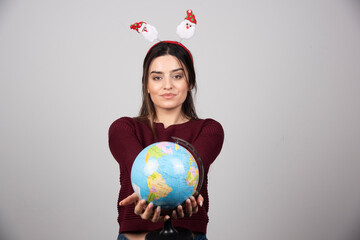 Young woman in Christmas headband holding an Earth globe