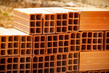 Detalhe de tijolos empilhados.
Tijolos cerâmicos dispostos em pilhas e armazenados ao ar livre para venda.