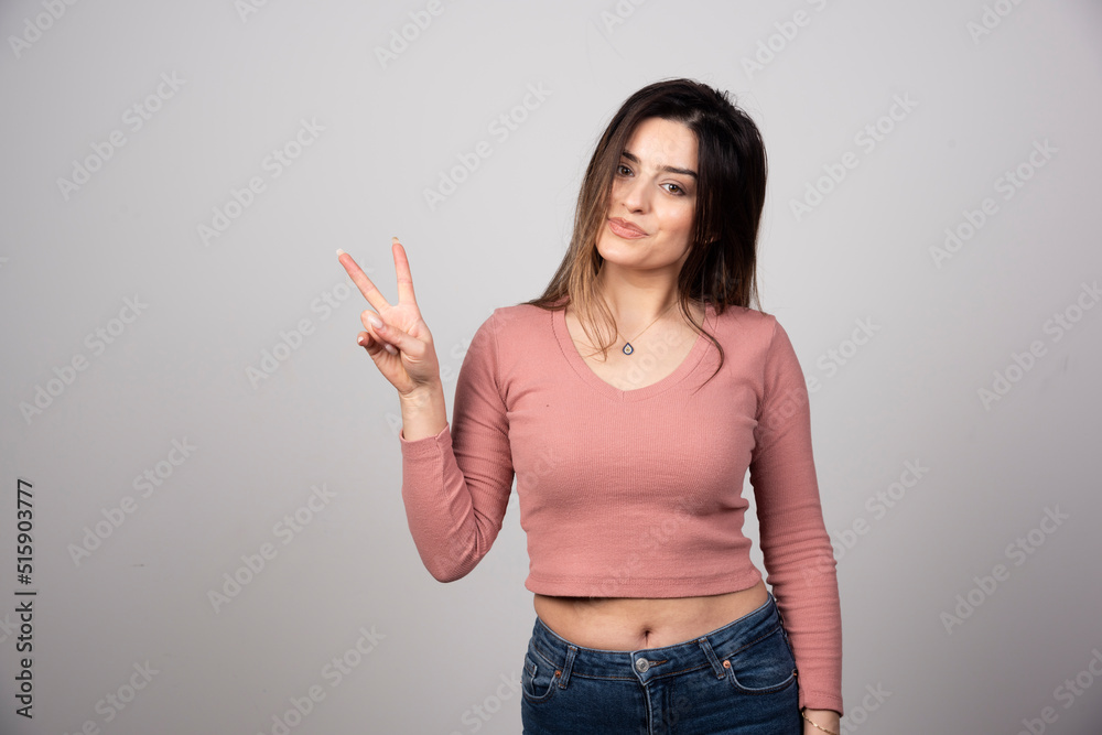 Wall mural A young woman showing peace hand sing