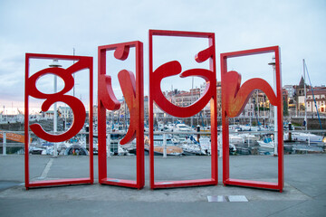 Monument called "letronas" with the name of the city, located in the marina of Gijón, Spain